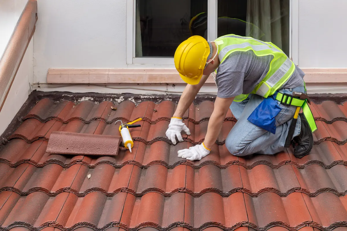 Roofer fitting new clay tiles on a pitched roof